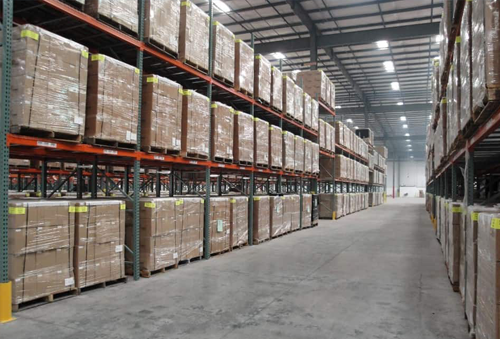 A logistics warehouse aisle with boxes on three tiered shelves